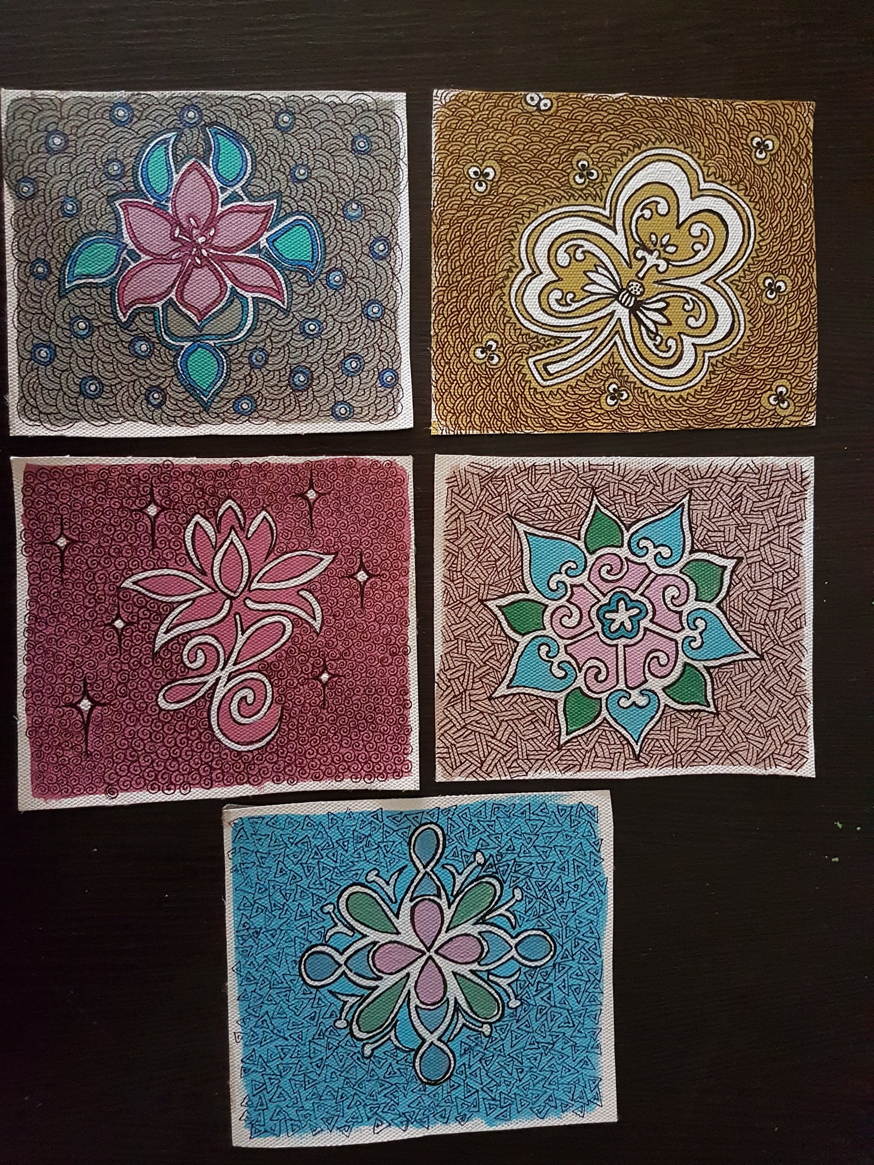 Five small square paintings with floral and ornamental motifs arranged together.